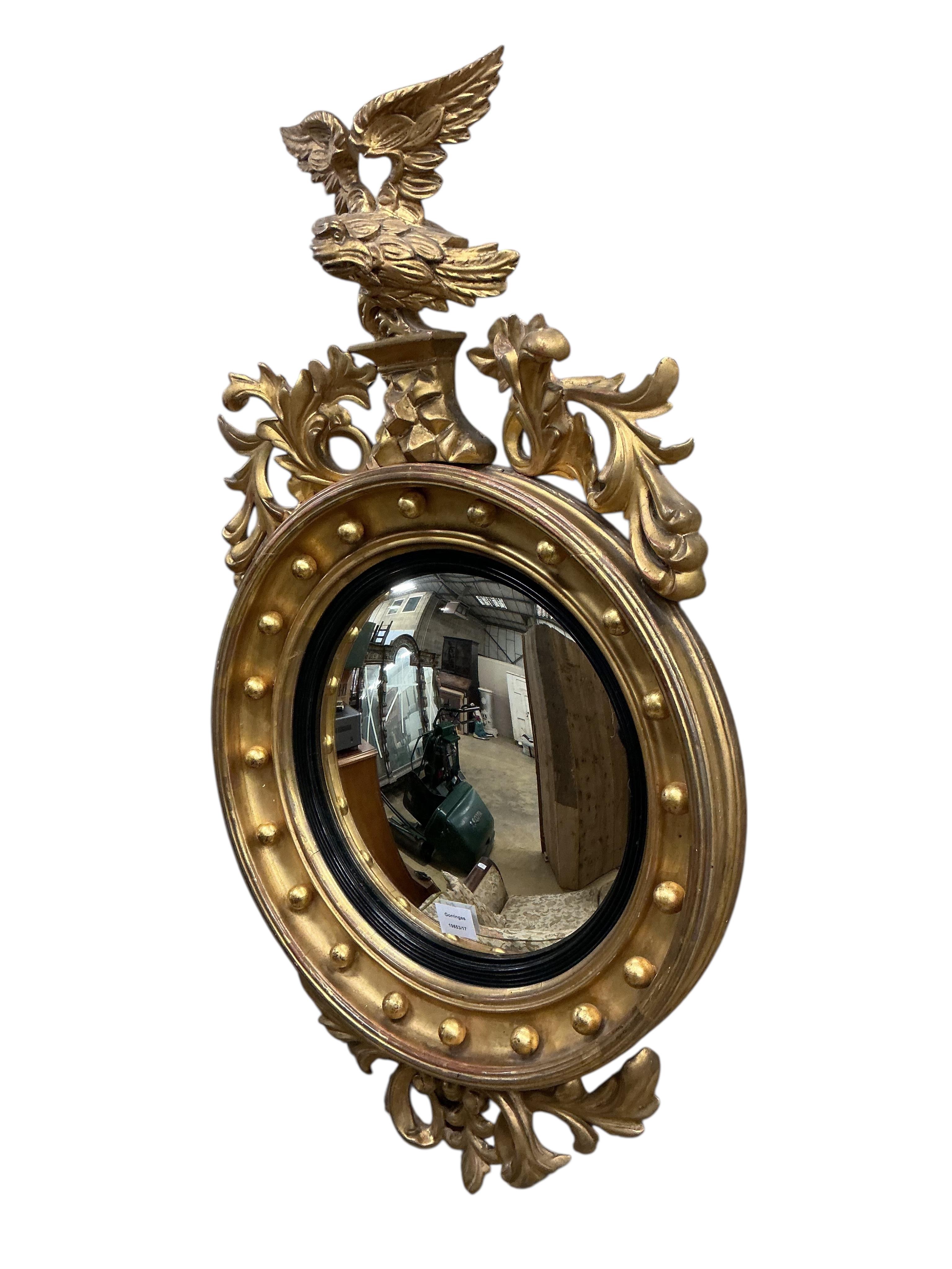 A Regency carved giltwood and composition convex wall mirror, with eagle surmount, width 54cm, height 96cm